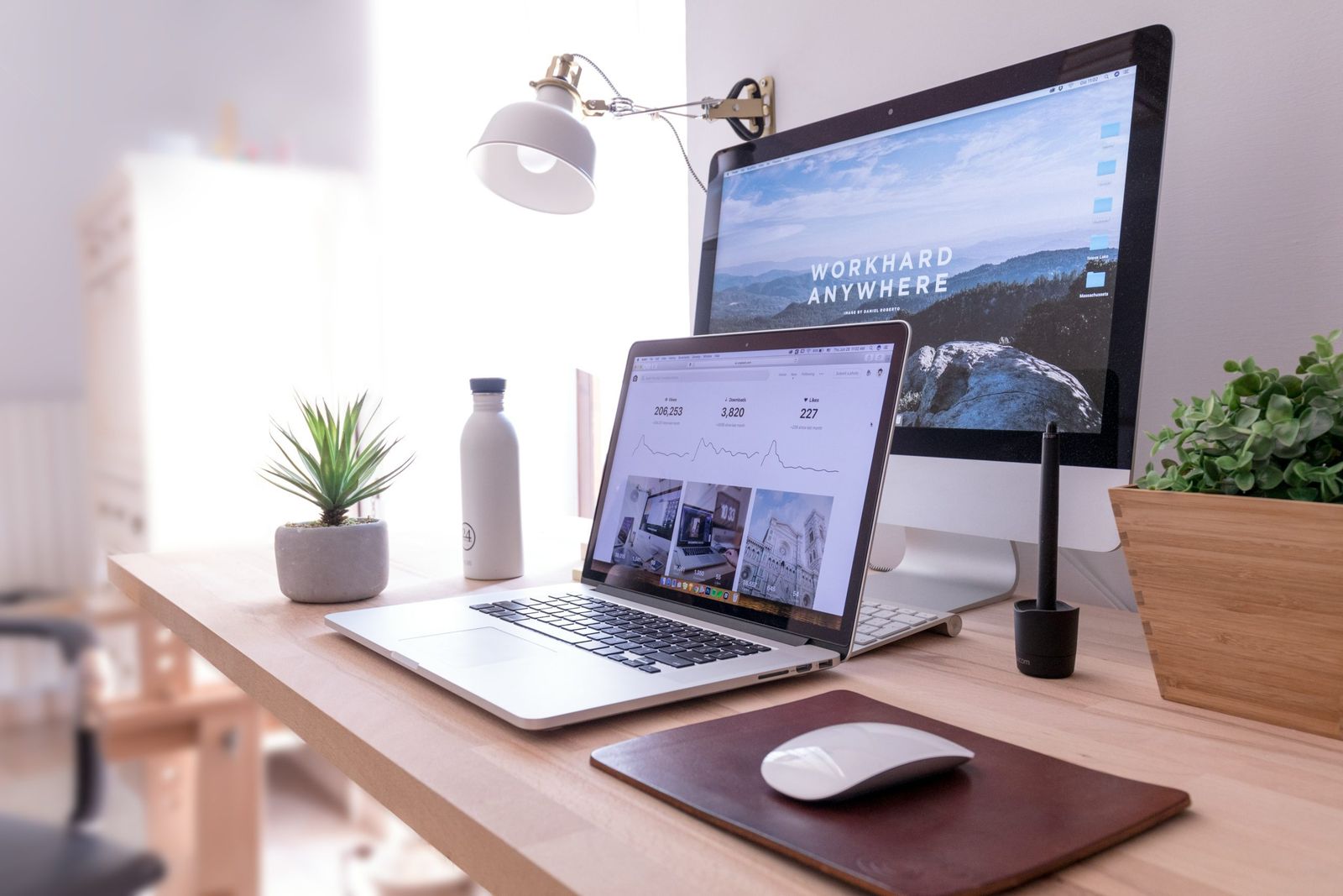 A desk with a laptop and monitor displaying analytics dashboards, set up for SEO tools work.